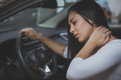 Woman grabbing her neck in pain of whiplash from being rear-ended by another vehicle.