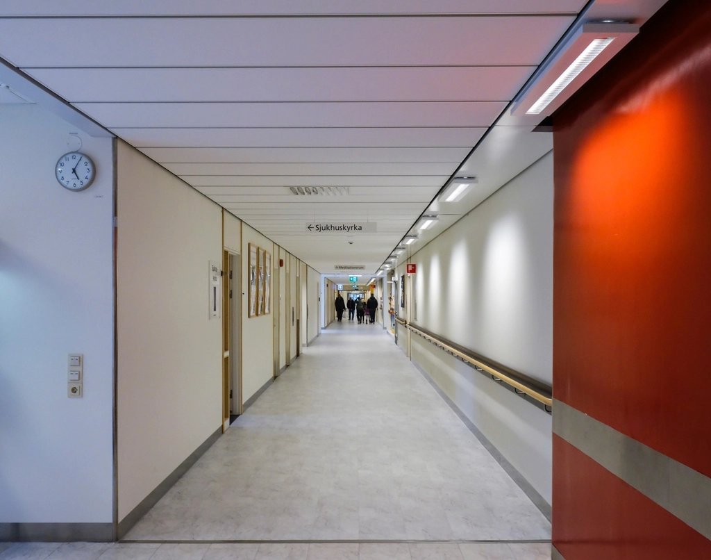 Bright modern hospital corridor with distant staff and visitors, clean and neutral